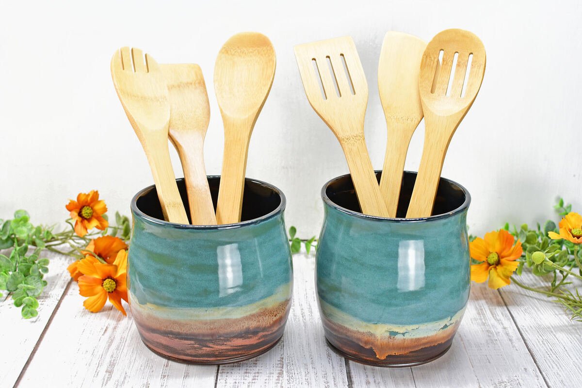 Two small crocks holding a few wooden spoons and spatulas